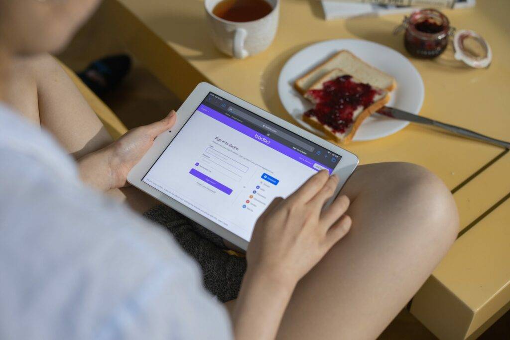 Tablet on someone's lap with breakfast on a table in the background