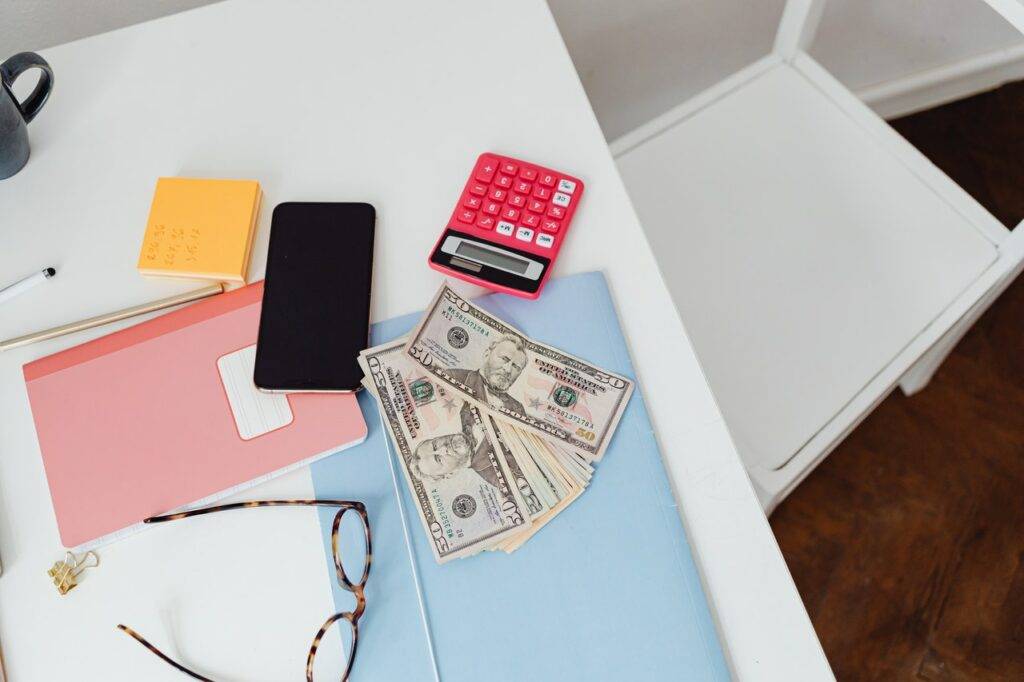 Table with money, phone, calculator and glasses on it
