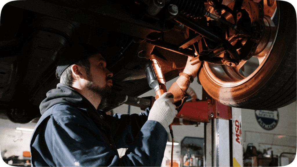 A man fixing the underside of a car in a workshop